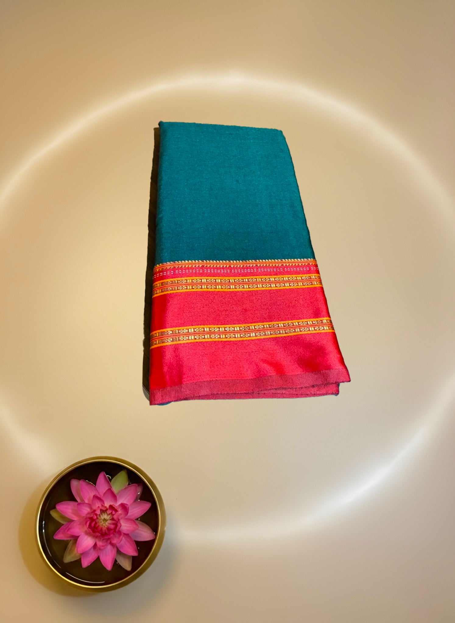 Teal and red saree with a pink flower on a white background